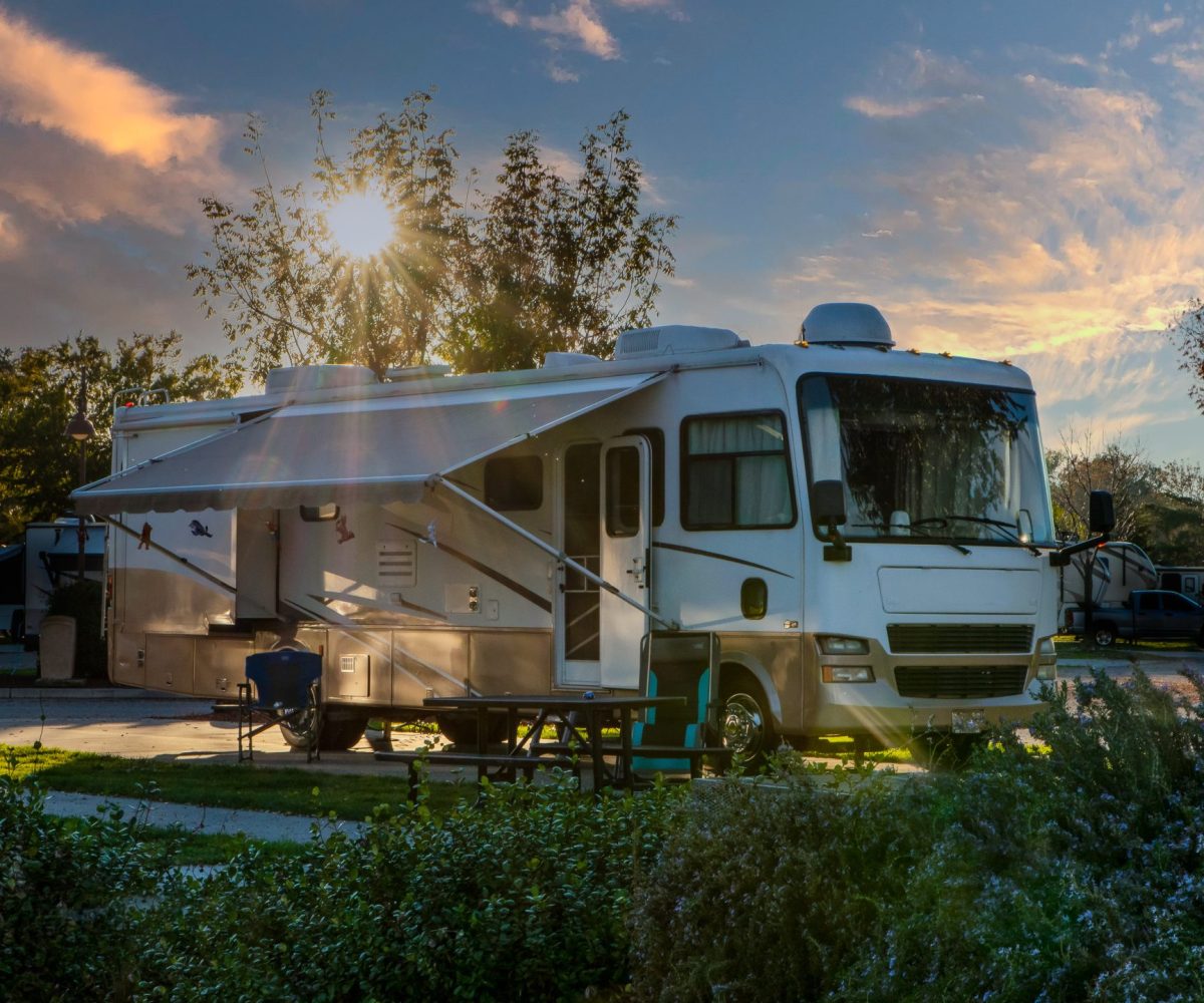 Sunburst through the tree above a Rv parked at a campsite